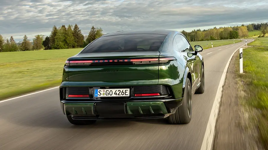 Der Porsche Cayenne Electric fährt auf einer Landstraße, von hinten fotografiert.