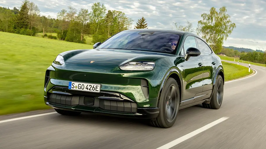 Der Porsche Cayenne Electric fährt auf einer Landstraße, von vorne fotografiert.