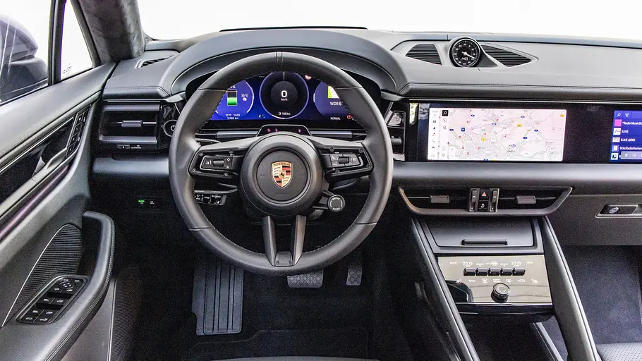 Das Cockpit des Porsche Macan zeigt ein Lenkrad, digitale Instrumente, einen Navigationsbildschirm und eine schwarze Mittelkonsole.