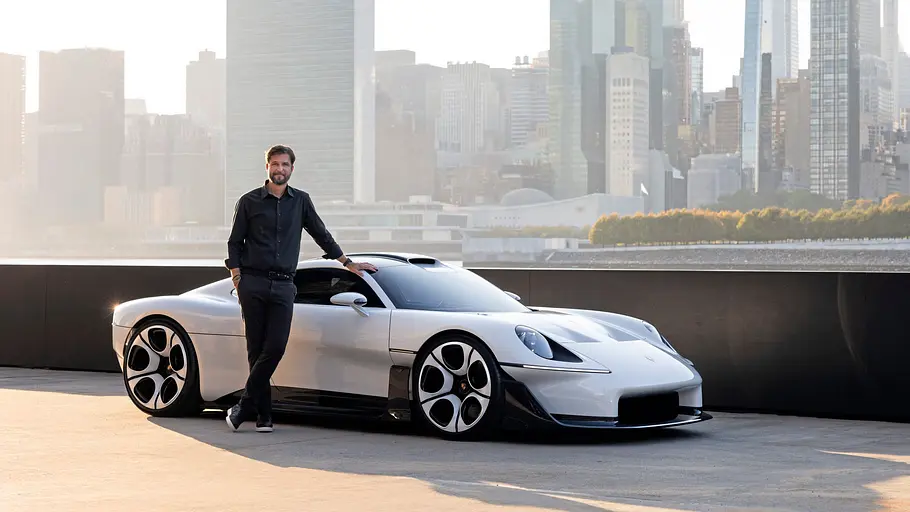 Porsche Mission S steht vor der Skyline von New York, fotografiert von schräg vorn. Der Chefdesigner lehnt an der Beifahrertür.