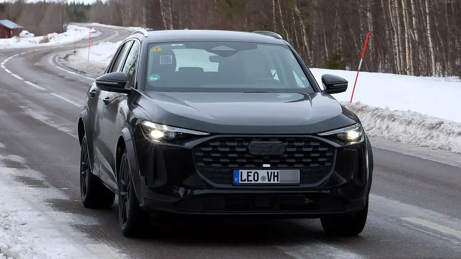 Der Porsche Octan fährt als Mule mir der Karosserie es Audi Q5 auf einer Landstraße, von vorne fotografiert.