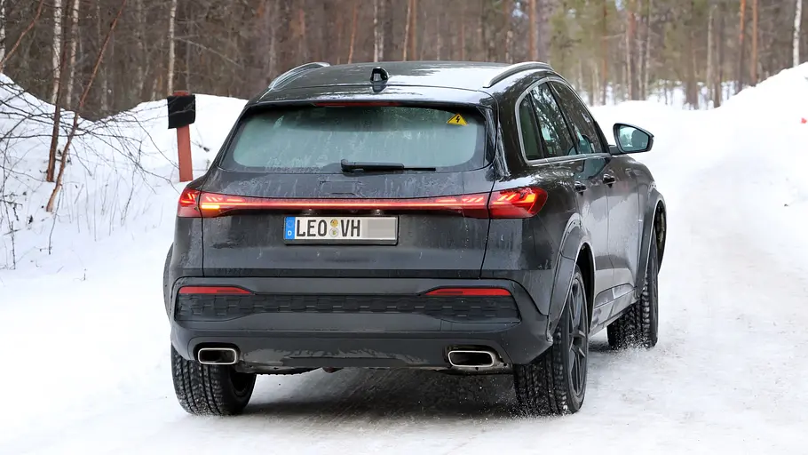 Der Porsche Octan fährt als Mule mit der Karosserie des Audi Q5 auf einer Landstraße, von hinten fotografiert.