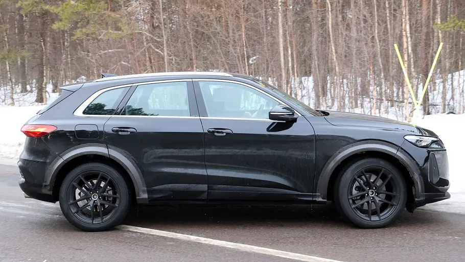 Der Porsche Octan fährt als Mule mit der Karosserie des Audi Q5 auf einer Landstraße, von rechts fotografiert.