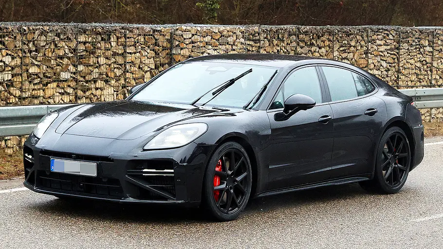 Porsche Panamera Facelift (2026) Blick von schräg vorne auf den fahrenden Erlkönig des Porsche Panamera Facelift (2026).