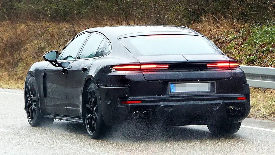 Porsche Panamera Facelift (2026) Blick von schräg hinten auf den fahrenden Erlkönig des Porsche Panamera Facelift (2026).