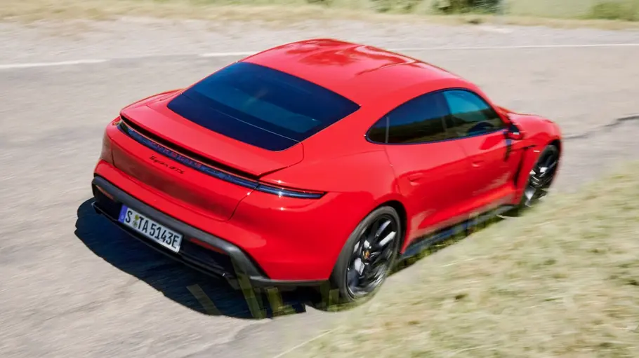 Porsche Taycan GTS fährt auf einer Straße, Ansicht von hinten rechts.