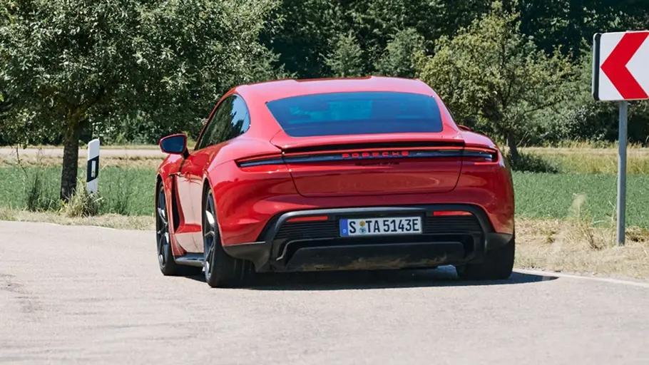 Porsche Taycan GTS fährt auf einer Straße, Ansicht von hinten.