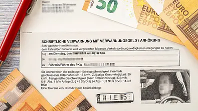 Ein Bußgeldbescheid mit Blitzerfoto. Am Rande des Bildes sind 50-Euro-Geldscheine zu sehen. - Foto: Imago