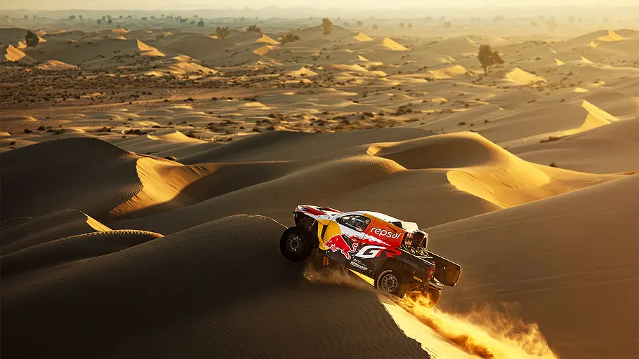Rallye Dakar 2026 Blick auf die Dünenlandschaft in der Wüste Saudi-Arabiens. In Vordergrund passiert ein Dakar-Truck die staubigen Dünen-Kämme.