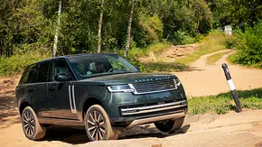 Die Außenaufnahme zeigt den Range Rover Electric stehend im Gelände. - Foto: Land Rover Die Außenaufnahme zeigt den Range Rover Electric stehend im Gelände. - Foto: Land Rover