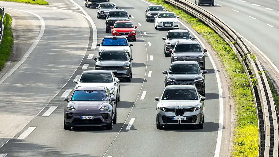 Autos und Lastwagen fahren auf einer mehrspurigen Straße mit getrennten Fahrbahnen. Rechts zweigt eine Ausfahrt ab.