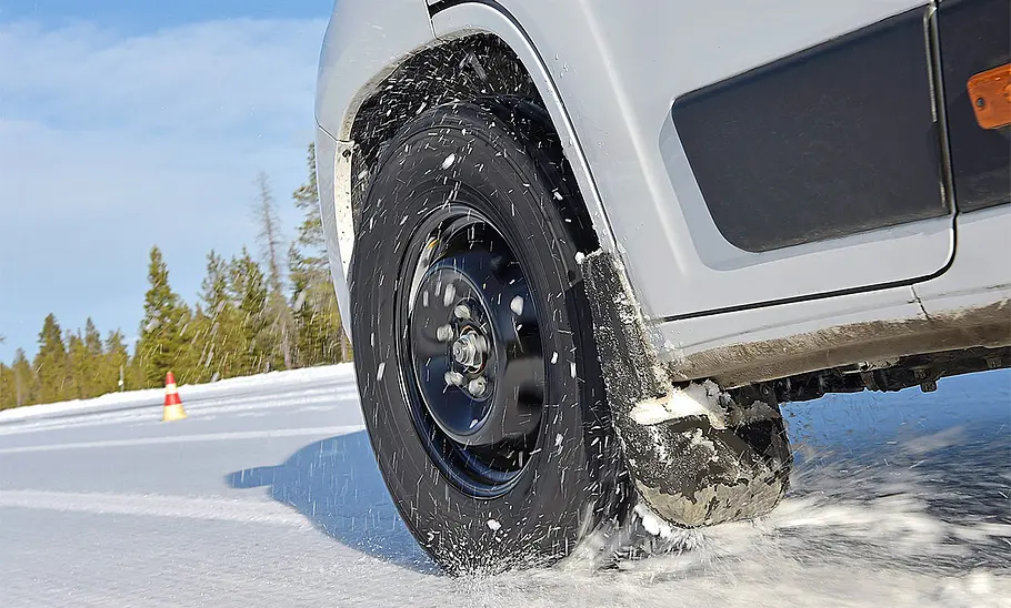 Das Bild zeigt den Ablauf des Traktionstests. Zu sehen ist ein leicht eingeschlagenes Vorderrad des fahrenden Wohnmobils im Schnee.