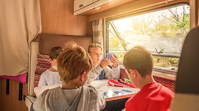 Vier Kinder spielen ein Kartenspiel in einem Wohnmobil - Foto: iStock/Antonio Suarez Vega