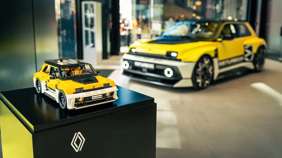 Der Lego Renault 5 Turbo 3E auf einem Podest vor einem echten Renault 5 Turbo 3E in einem Renault-Showroom.