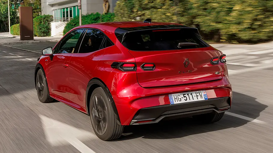 Der Renault Clio fährt durch eine Stadt, von hinten links fotografiert.