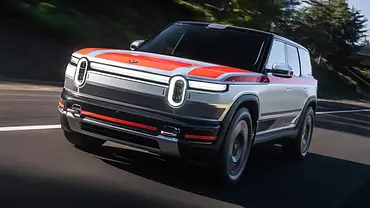 Der Rivian R2 fährt als Prototyp auf einer Landstraße, von vorne fotografiert. - Foto: Rivian Der Rivian R2 fährt als Prototyp auf einer Landstraße, von vorne fotografiert. - Foto: Rivian