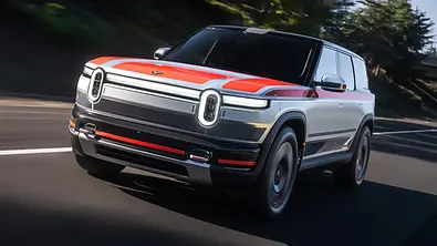 Der Rivian R2 fährt als Prototyp auf einer Landstraße, von vorne fotografiert. - Foto: Rivian