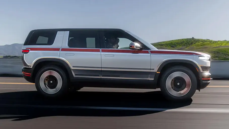 Rivian R2 Der Rivian R2 fährt als Prototyp auf einer Landstraße, von rechts fotografiert.