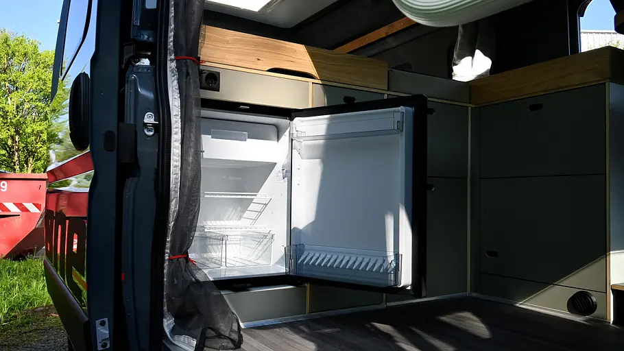 Rocket One L Blick durch die geöffnete Schiebetüre auf den Küchen-Unterschrank samt geöffnetem Kühlschrank im Rocket One L.