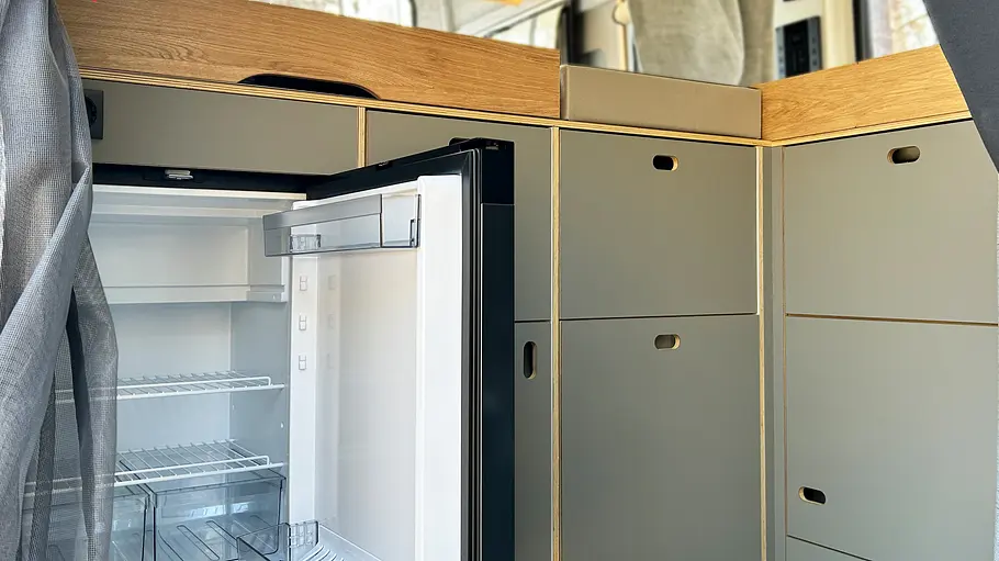 Der Unterschrank der Küche des Rocket One XL samt geöffnetem Kühlschrank im Detail.