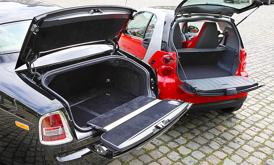 Der Rolls-Royce Phantom und der Smart Fortwo nebeneinander, in der Ansicht auf den Kofferraum.