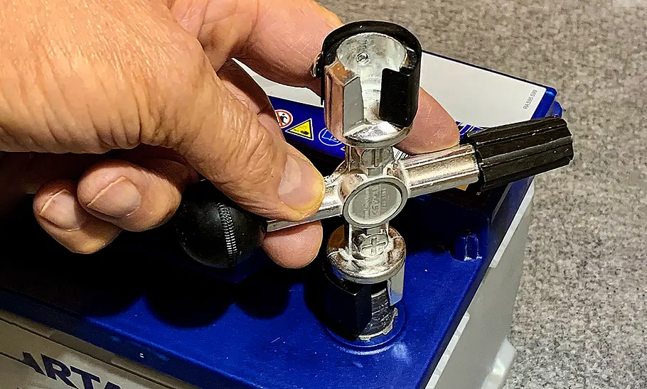 Der Batteriepol-Reiniger in der Hand eines Menschen.