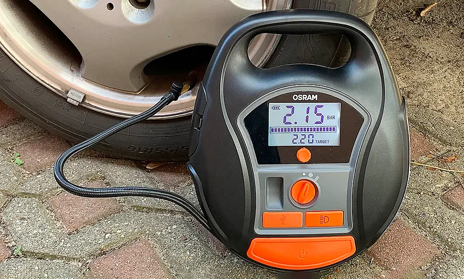 Der Osram TYREinflate 6000 vor einem Autoreifen.