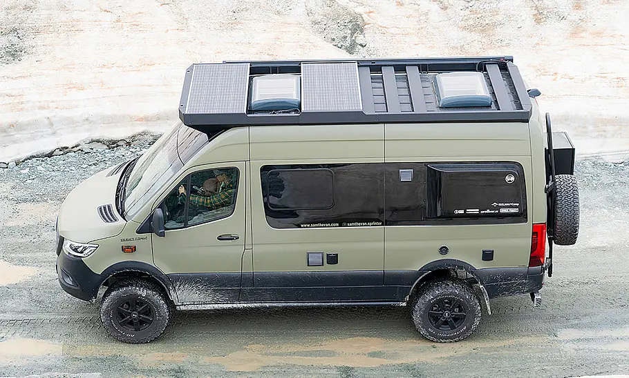 Sam the Van (2025) Sam the Van (2025) stehend, von der linken Seite aus leicht erhöhter Position fotografiert. Das Fahrzeug steht auf einer Schotterstraße, daneben liegt Schnee.