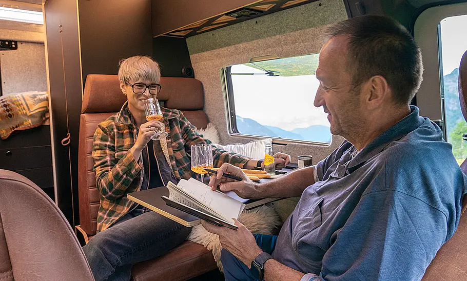 Sam the Van (2025) Maria Bauer (links) und Thomas Geiger (rechts) in der Sitzgruppe des Sam the Van (2025) sitzend.