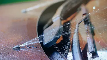 Das Detailbild zeigt die Scheibenwaschanlage eines roten Autos in Betrieb. Die Düsen spritzen Scheibenwaschwasser auf die Windschutzscheibe. - Foto: iStock/Titushkin Das Detailbild zeigt die Scheibenwaschanlage eines roten Autos in Betrieb. Die Düsen spritzen Scheibenwaschwasser auf die Windschutzscheibe. - Foto: iStock/Titushkin