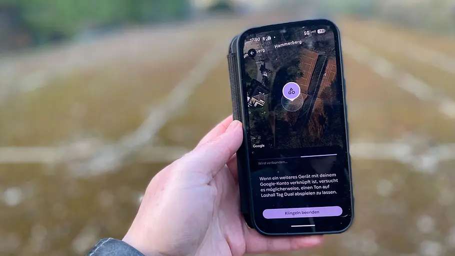 Testerhand mit Smartphone beim Schlüsselfinder-Test, fotografiert von der Seite.