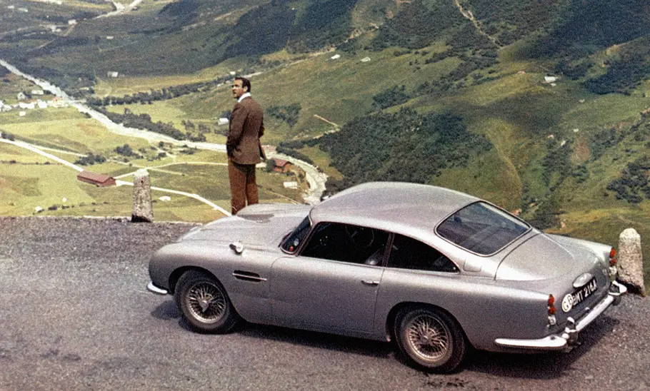 Der Aston Martin DB5 von oben, davor steht Sean Connery, der James Bond verkörpert hat.