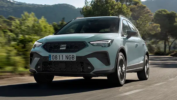 Das Seat Arona Facelift fährt auf einer Landstraße, von vorne links fotografiert. - Foto: Seat