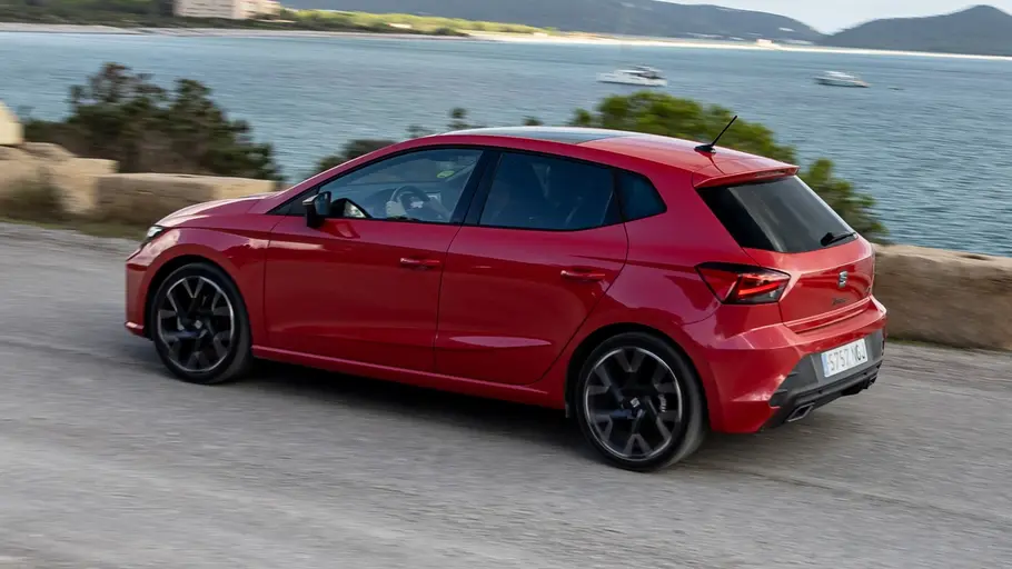 Seat Ibiza Facelift (2026) Der Seat Ibiza fährt über eine Landstraße an einem Gewässer, fotografiert von schräg hinten.