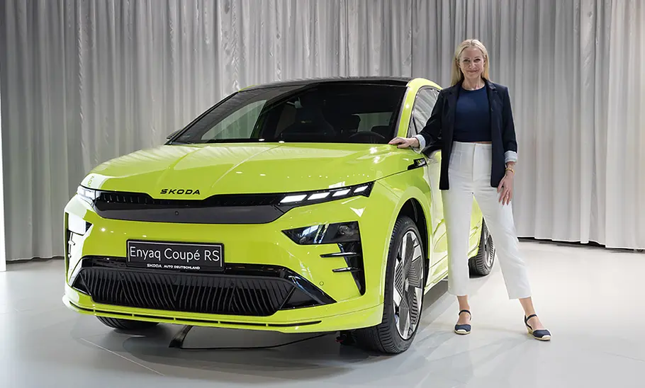 Skoda Enyaq RS Der neue Skoda Enyaq RS stehend im Studio in der Frontalansicht, daneben Redakteurin Adele Moser.