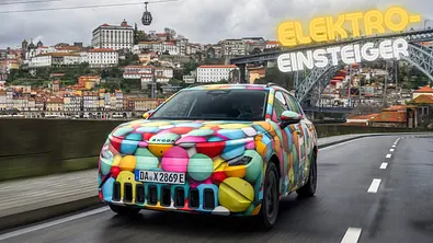 Skoda Epiq als getarntes Vorserienfahrzeug fahrend mit Stadt Porto im Hintergrund. - Foto: AUTO ZEITUNG