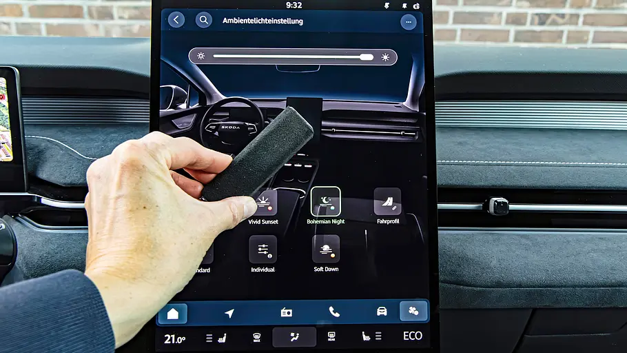 Touchscreen des Skoda Peaq mit dem Menü zur Ambientebeleuchtung, eine Hand hält einen Displayreiniger davor.