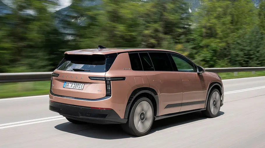 Skoda Peaq in Bronze von hinten fahrend auf einer Landstraße mit Bäumen im Hintergrund.