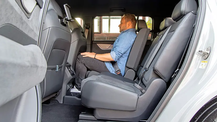 Ein Mann sitzt in der zweiten Sitzreihe des Skoda Peaq, Blick durch die geöffnete hintere Tür.