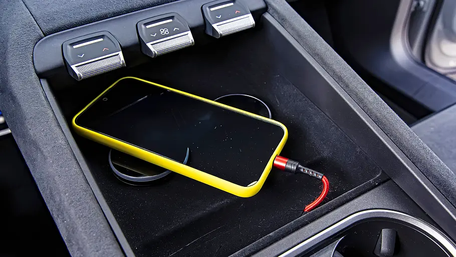 Mittelkonsole des Skoda Peaq mit Smartphone auf der Ablage und drei Drehreglern darüber.