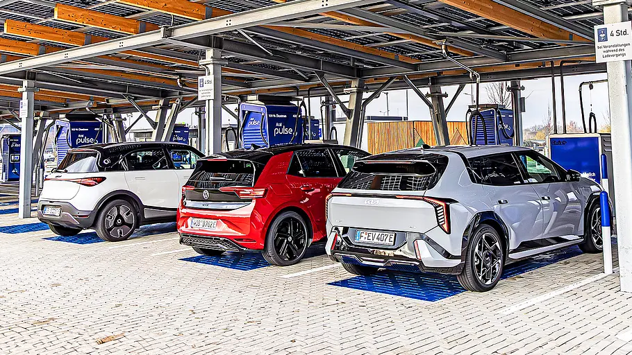 Blick von schräg hinten auf die drei elektrischen Kompakten Smart #1, VW ID. 3 GTX und Kia EV4, die an Schnellladesäulen tanken.