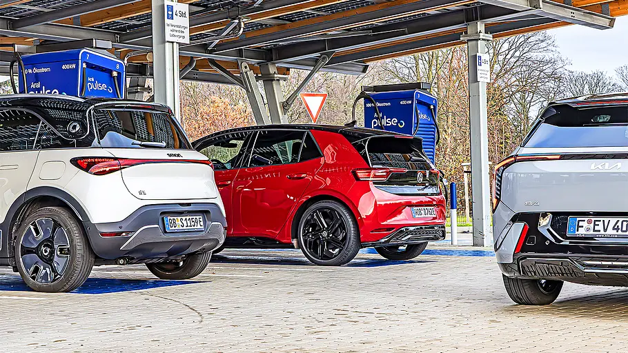 Blick von schräg hinten auf die drei elektrischen Kompakten Smart #1, VW ID. 3 GTX und Kia EV4, die an Schnellladesäulen tanken.