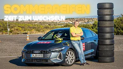 Testredakteur vor Reifenstapel und Auto auf Testgelände. - Foto: AUTO ZEITUNG