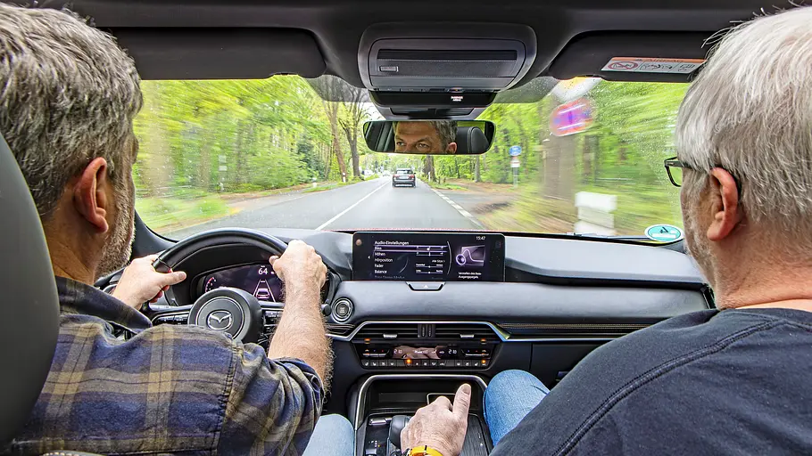 Zwei Personen sitzend im Auto fotografiert.