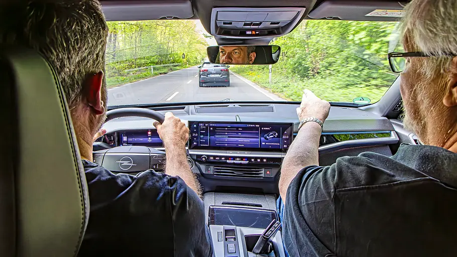 Zwei Personen sitzend im Auto von hinten fotografiert.
