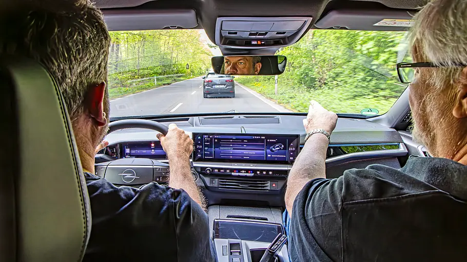 Zwei Personen sitzend im Auto fotografiert.
