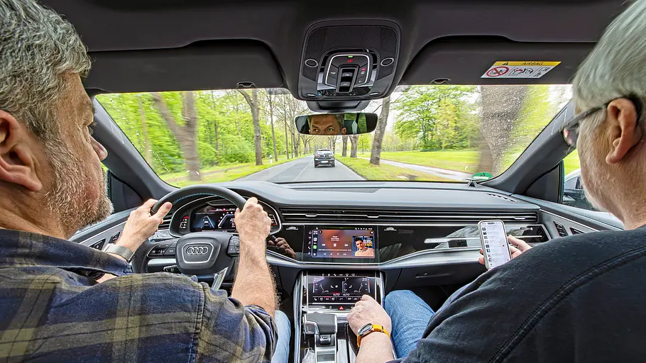 Zwei Personen sitzend im Auto fotografiert.