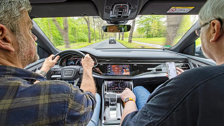 Zwei Personen sitzend im Auto von hinten fotografiert.
