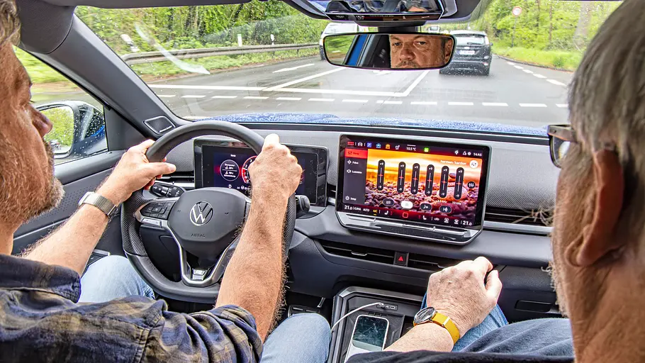 Zwei Personen sitzend im Auto fotografiert.