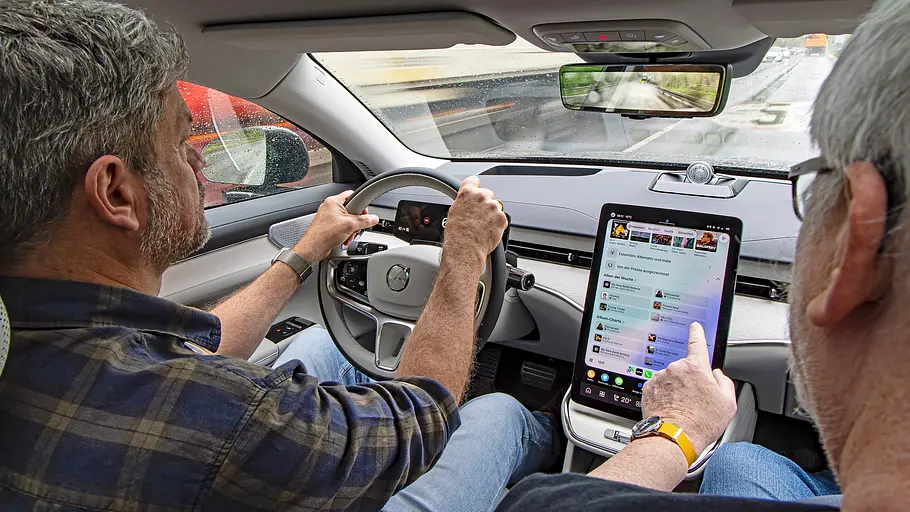 Zwei Personen sitzend im Auto fotografiert.